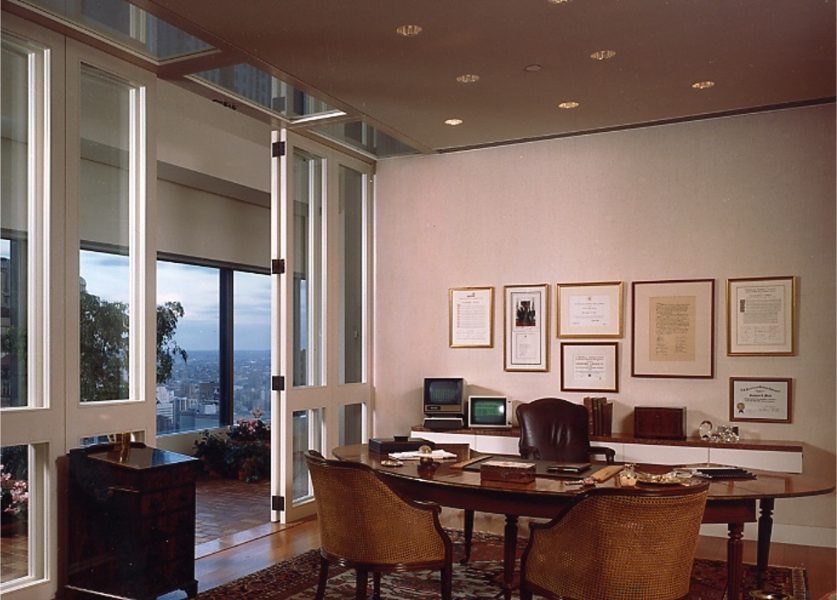 Private offices on the executive floor open to an enclosed walkway that surrounds the building. Note that some of the recessed light fixtures are “downlight/wall washers”. As such, they not only light the desk surfaces below. They also evenly wash the back wall, thereby avoiding distracting scallops that would have been created by using normal recessed downlights.